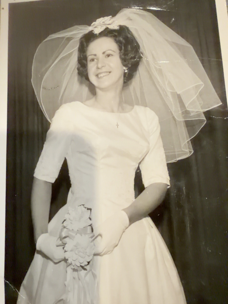 Bridal portrait of Carol Rudy Samuel holding a bouquet on her wedding day in August 1965.
