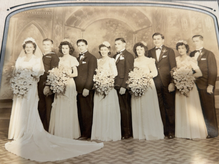 A large wedding party in formal clothing, with Viola and Frank Samuel as the couple at the far right.