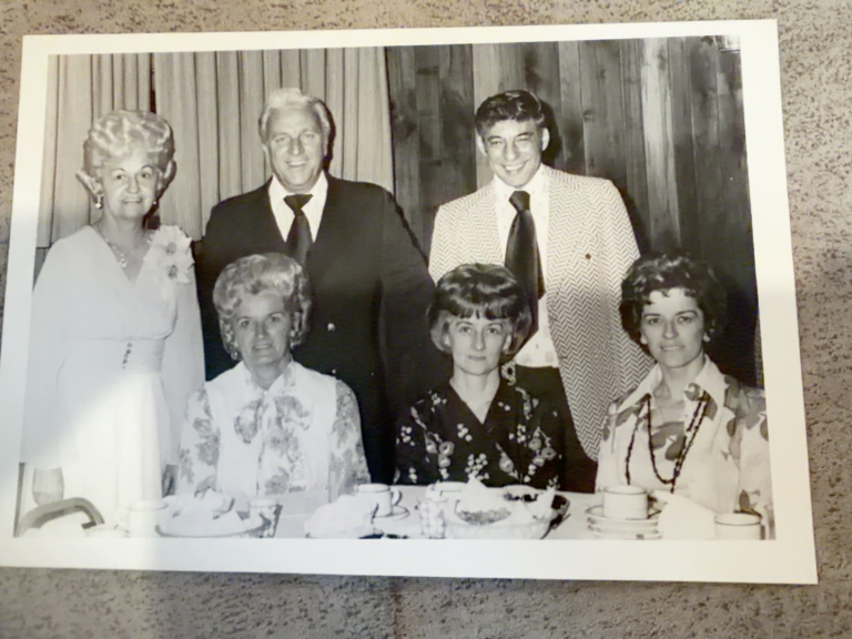 Six people gathered around a table at Viola Samuel’s retirement from DuPont: Sophie Winkler, Jane, and Millie Trent seated in front; Viola Samuel, Joe Trent, and Phil standing.